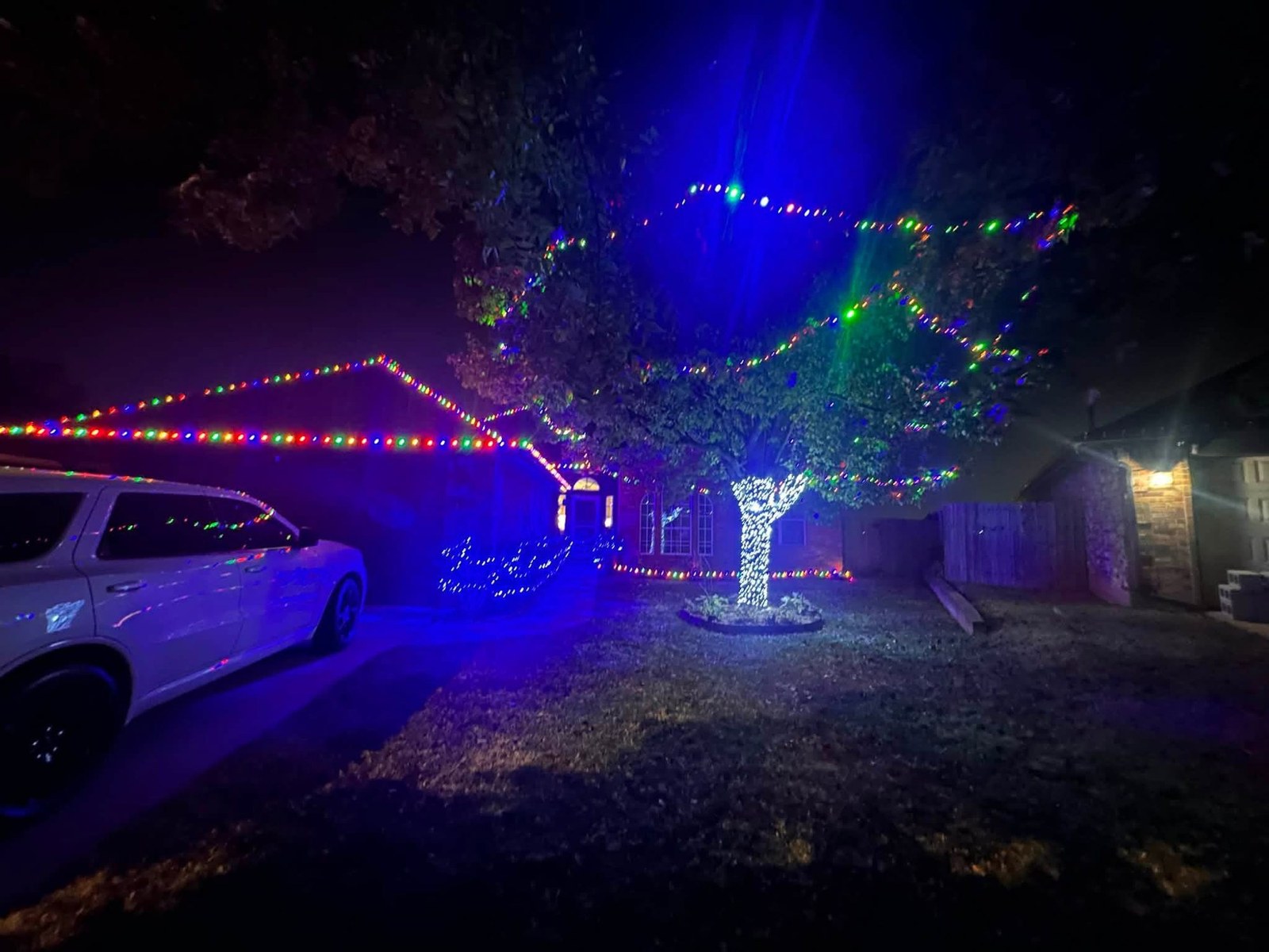 Multi-color roofline with a lit tree and blue lights at night